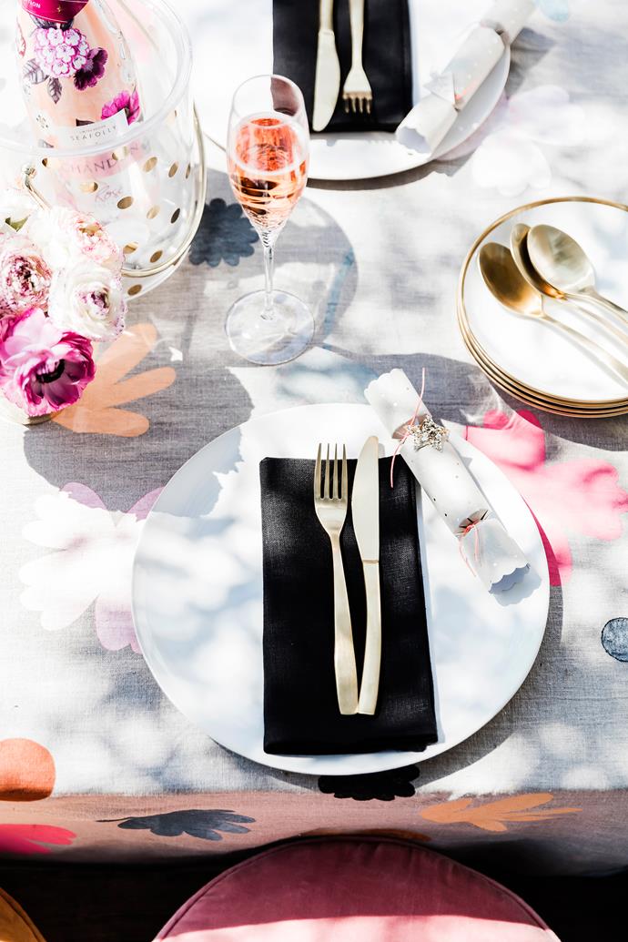 Black linen napkins create contrast against the pretty floral hand-printed tablecloth. A touch of gold ups the glamour.