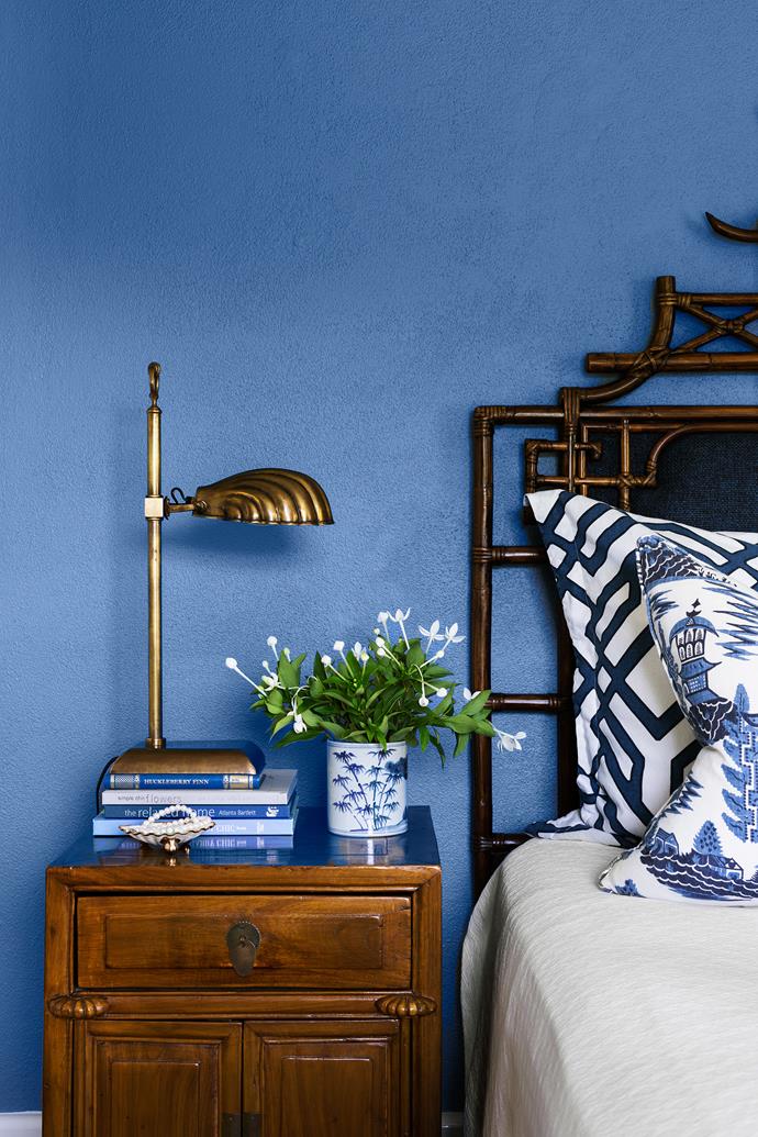 Brass, timber and dark-stained cane look resplendent against a wall in Dulux Blue Oar. Custom bedhead.