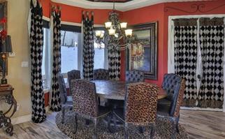 Dining room with red walls, leopard print chairs and checkered curtains.
