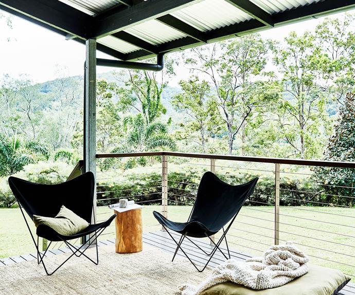 A pair of butterfly chairs on a verandah overlooking bushland