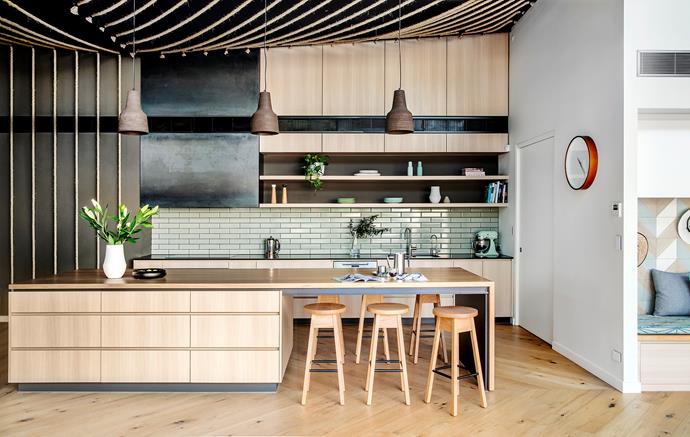Clean lines and high ceilings enhance the feeling of space. A butler's pantry is located behind the door at right. Custom Corten-steel rangehood. Splashback tiles, from Eco Tile Factory. 'Eva' pendant lights, from Espo Lighting. Benchtops in American oak (island) and Caesarstone Raven.