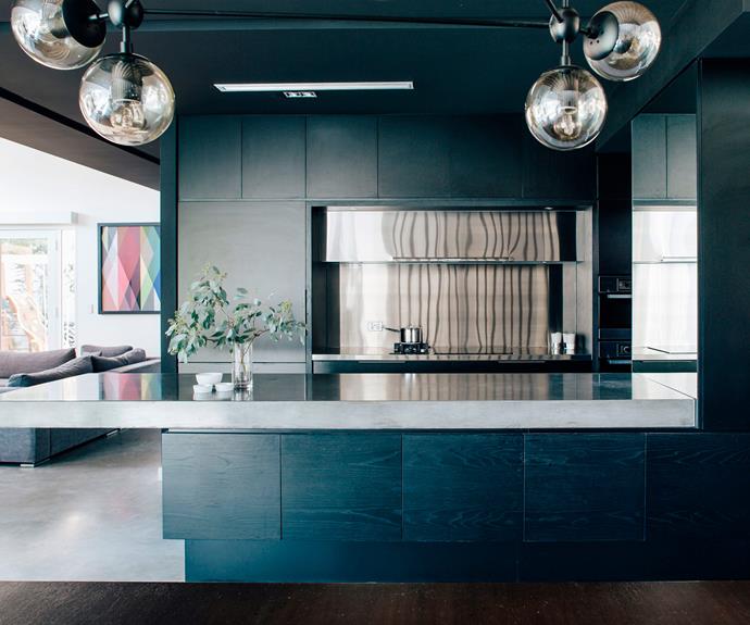 The kitchen is painted a dramatic black, designed to function as both a casual cooking area and a space for entertaining. | *Photo: Christopher Morrison*