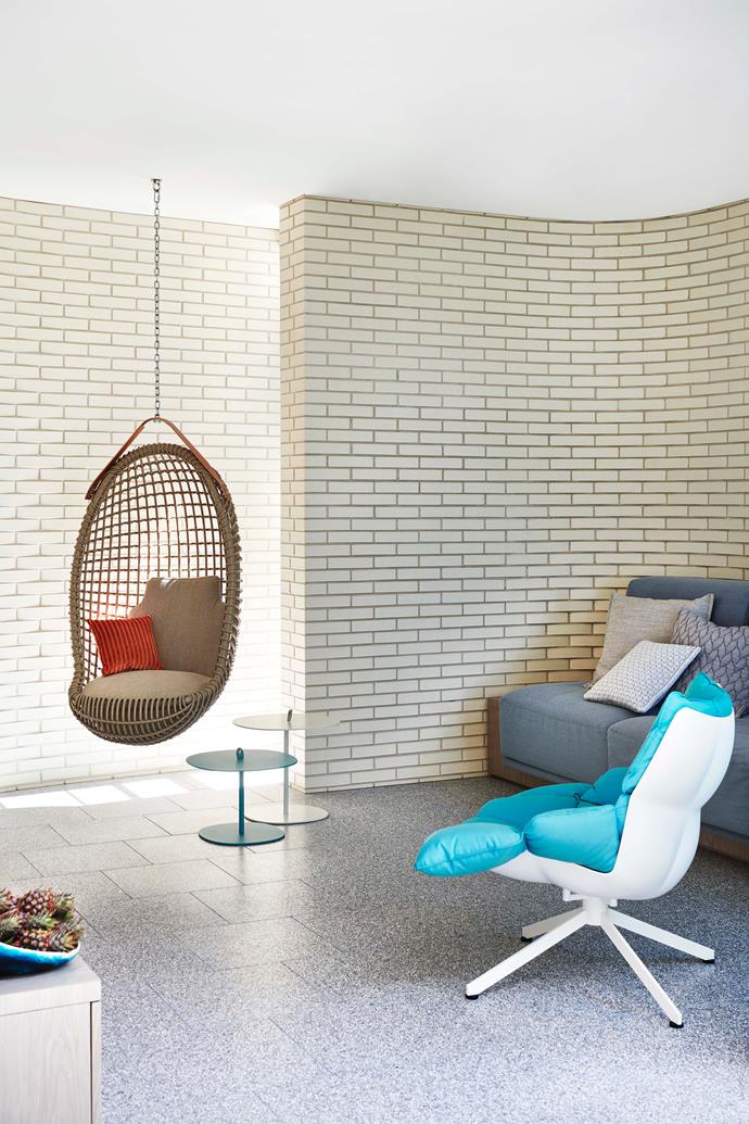The corners of the living room are softened by the curving, exposed brick wall. B&B Italia 'Husk' armchair by Patricia Urquiola from Space, and Bonacina 1889 'Eureka' hanging chair from De De Ce. Bowl from Dinosaur Designs.