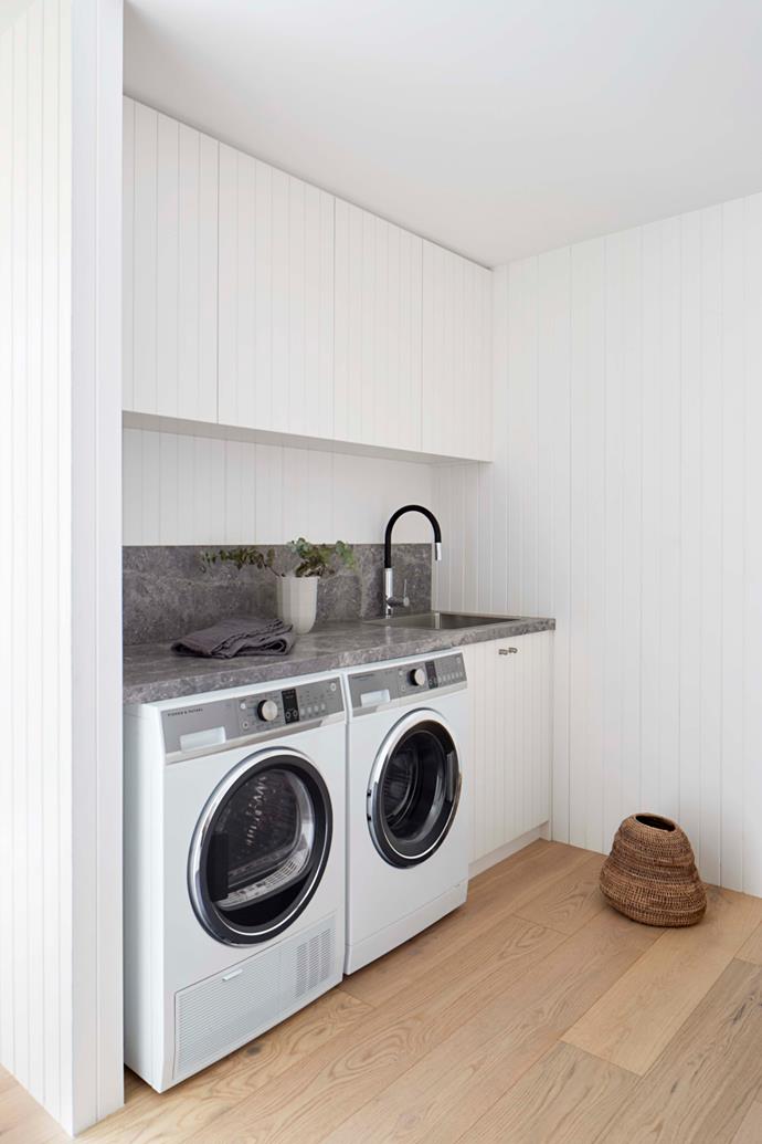 In the laundry, a Fisher & Paykel washer and heat-pump dryer are tucked under a limestone bench.
