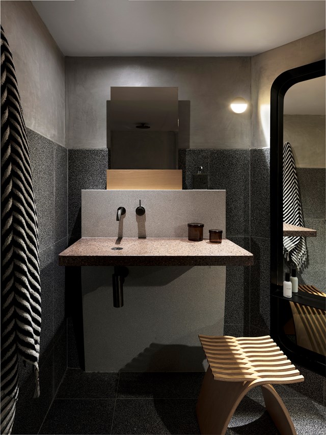 Terrazzo tiles layered with rendered cement walls lend a dark, sensual appeal to this luxurious [apartment designed by Amber Road](https://www.homestolove.com.au/sydney-penthouse-apartment-by-amber-road-19349|target="_blank"). The designer says "An early decision was to leave the cement base and services raw and exposed, with a simple palette of terrazzo, timber and stone." *Photo: Felix Forest / Styling: Alicia Sciberras / Story: Belle*
