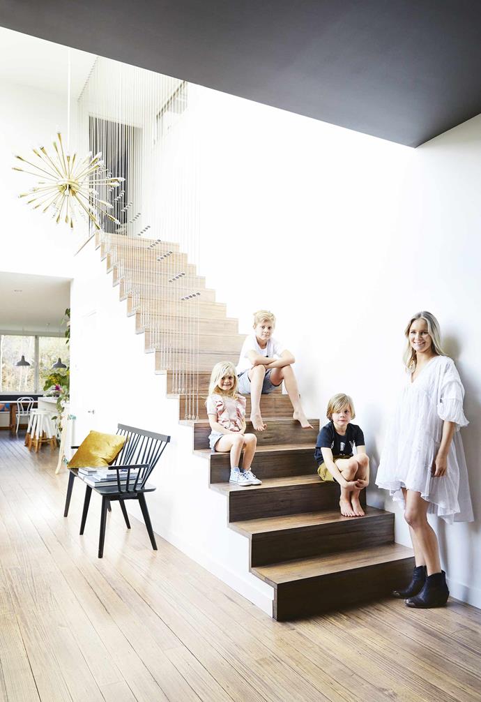 "Although the ceilings are tall, the windows were pretty small in comparison, which made the rooms feel dark and dingy," says Casey. "We wanted to [bring in more light](https://www.homestolove.com.au/the-panel-how-to-make-the-most-of-natural-light-16759|target="_blank") and create an open space where we could hang out as a family." The couple were also keen to create views of the garden from the kitchen and level access to the deck, making it more accessible for the kids.<br><br>**Portrait** Casey stands beside Olive, Alfie and Monty on stairs with vertical steel railings. The pendant light was a vintage find.