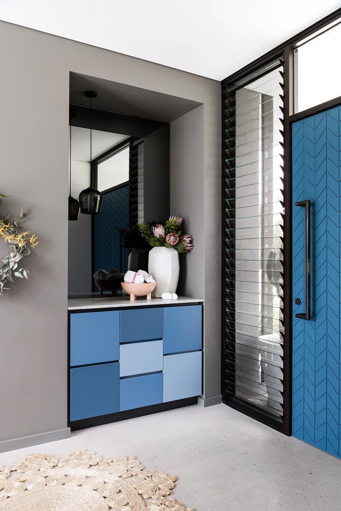 Blue and grey hues are paired throughout. The front door opens to a Mondrian-style arrangement of Laminex panels.