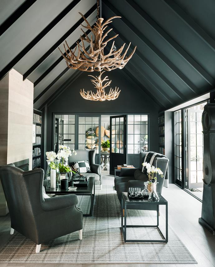 Matt-black paint on most of the walls and ceiling keeps this room  cosy. The fireplace is clad in the same oak as the floor. Antler chandeliers and grandfather clock, Restoration Hardware (US). Sofas covered in linen fabric from Westbury Textiles. Rug, Carpet World.