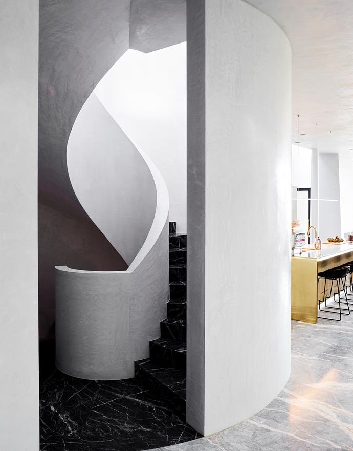 Light pours down the black marble spiral staircase from a domed skylight in [this Sydney home](https://www.homestolove.com.au/luxurious-transformation-of-a-former-factory-in-melbourne-6171|target="_blank") by Rob Mills Architecture & Interiors. The kitchen features a polished brass island and Moros 'Fjord' bar stools from Hub.
