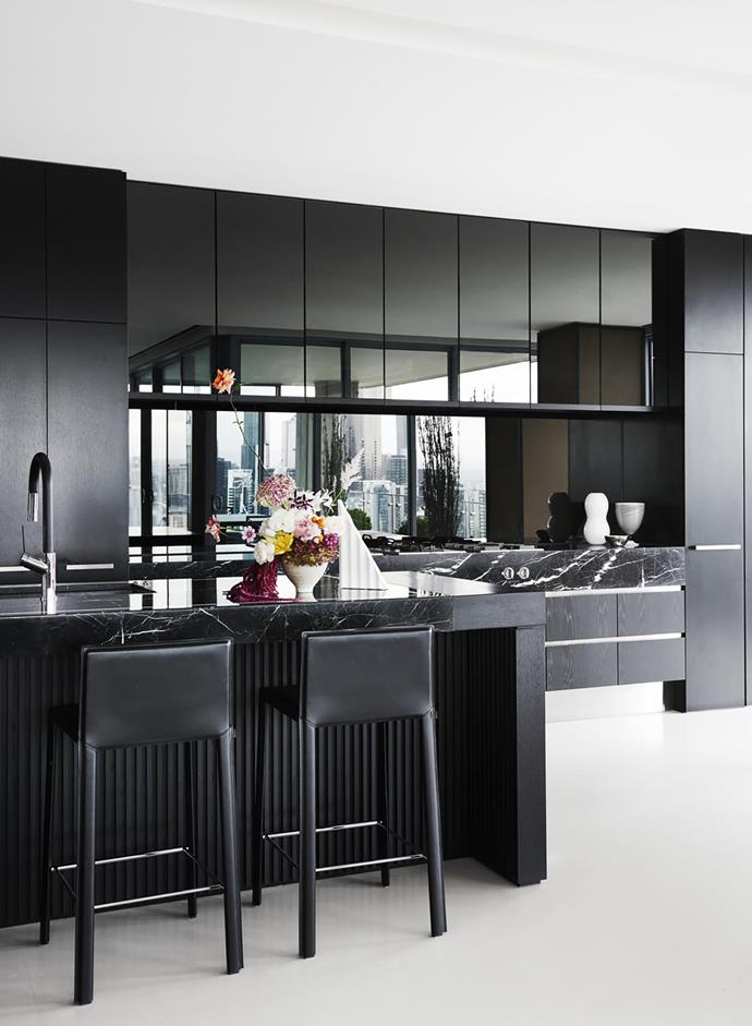 European oak cupboards with black japan finish and silver mirror splashback. Nero Marquina marble benchtops. Stools from Fanuli. Sculpture by Sean Meilak.
