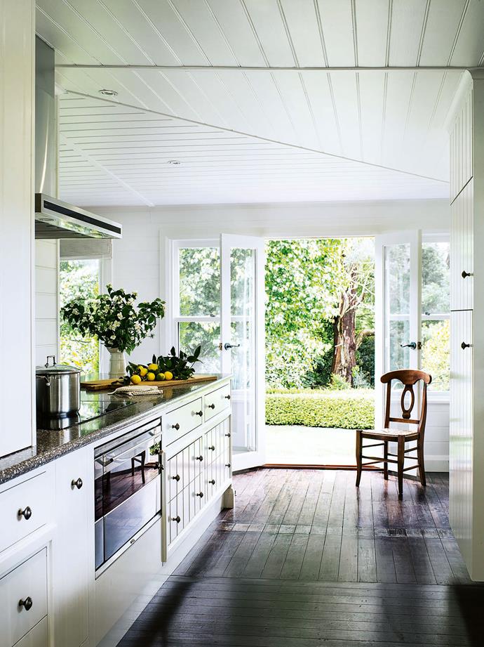 The pair re-configured the [kitchen into a split galley space](https://www.homestolove.com.au/galley-kitchen-inspiration-16688|target="_blank"), with the oven and cooktop at one end and a bar area at the other. Panelled cabinetry  in the kitchen builds on the home's Hampton's feel