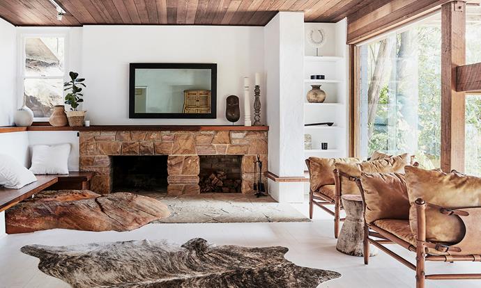 The downstairs living room is swathed in raw materials. A sandstone fireplace and large rock, which protrudes through the floor, are standout features.
