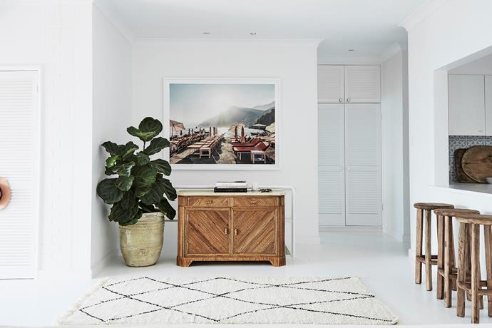The hallway next to the kitchen has been thoughtfully styled with an antique bamboo and marble sideboard, thriving [fiddle leaf fig plant](https://www.homestolove.com.au/tips-for-caring-for-fiddle-leaf-fig-trees-4923|target="_blank"), beni ourain rug and an eye-catching art print by Olivia's friend, Stuart Cantor.