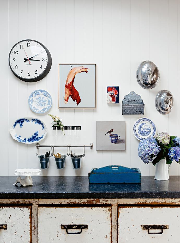 A collection of vintage china hangs above a rustic sideboard.