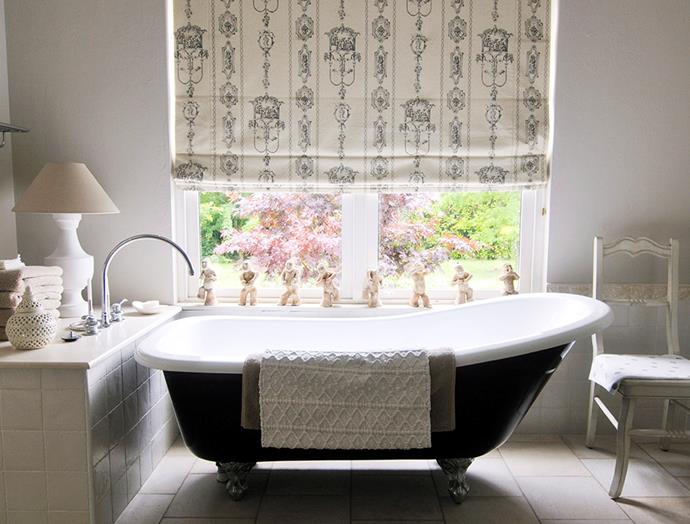 Keeping within the style of this country cottage, roman blinds have been used to dress this large bathroom window, embellished with a period print of course. *Image: Robert Reichenfeld / bauersyndication.com.au*