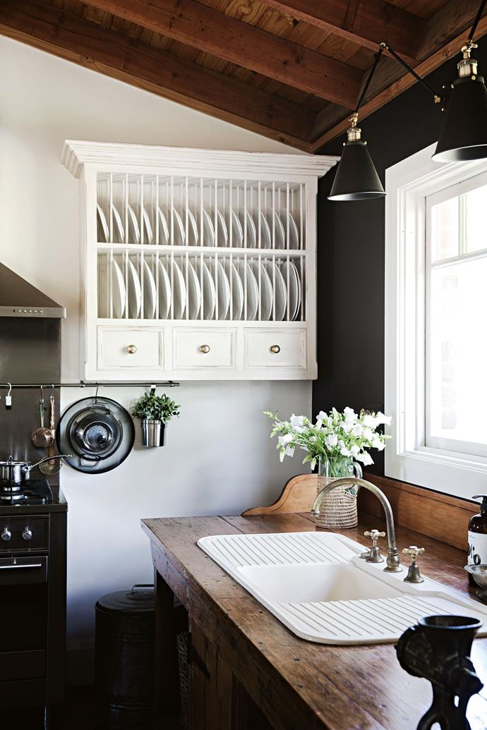 Old meets new in this [brick farmhouse](https://www.homestolove.com.au/brick-farmhouse-12079|target="_blank") on the outskirts of Sydney. Owner Heidi O'Rourke, who is drawn to rustic pieces, gave the kitchen a classic makeover with a modern edge. It features a black feature wall and a vintage workbench fitted with a sink. "[The kitchen] is a unique space with loads of natural light, which makes it a joy to be in," she says.