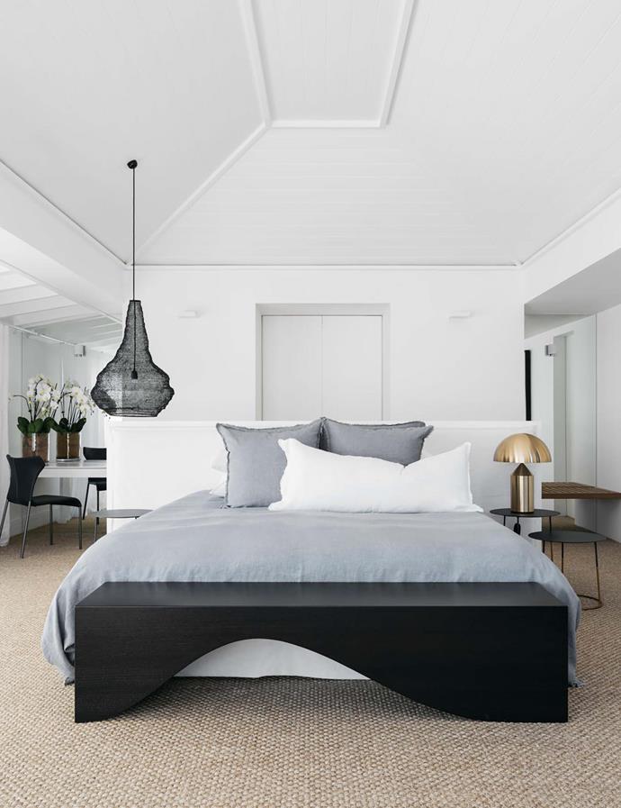 An 'Atollo' table lamp sits on a 'Nimbus II 40' bedside table in the main bedroom. Hale Mercantile Co. bed linen. B&B Italia 'Papilio' black leather chair from Space. Black wire crochet suspension light from Les Interieurs.