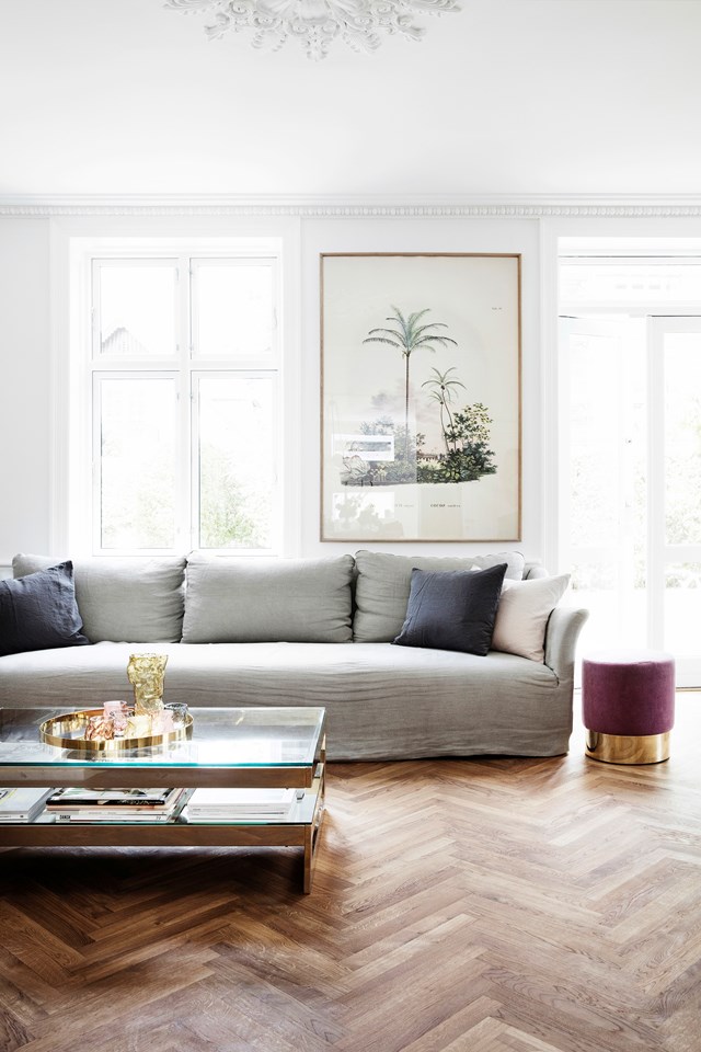 A collection of objects gather on a tray atop a glass and brass coffee table in the living room of [this fashion stylist's charming villa](https://www.homestolove.com.au/pernille-teisbaek-home-tour-copenhagen-20173|target="_blank").