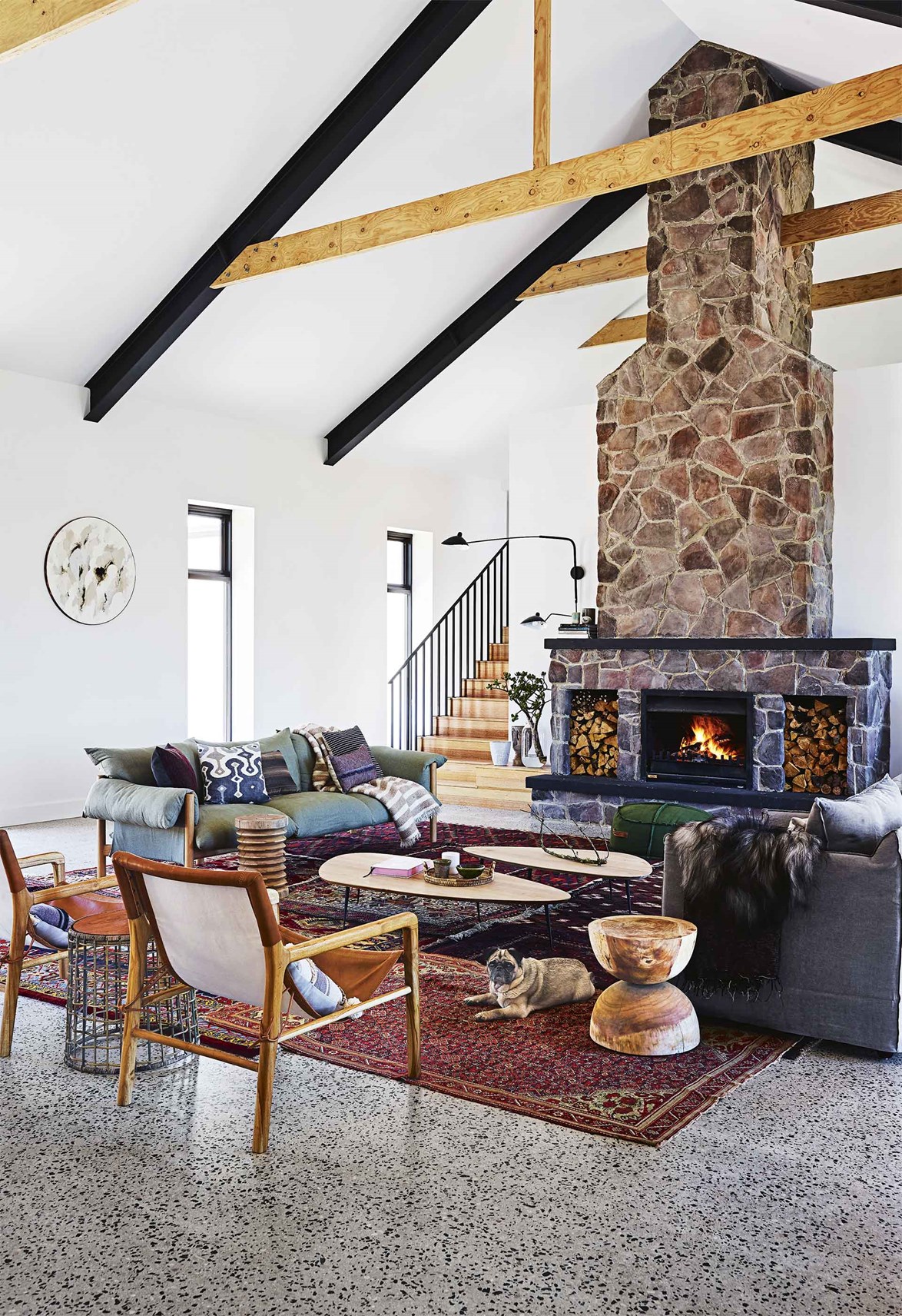 Designed as a space to relax with family and friends, this newly built fireplace blends rustic random stacked stone with exposed beams and a narrow mantle. The colour of the stone takes on a modern look as it cleverly ties to contemporary details of black beams, balustrading and polished concrete floors.