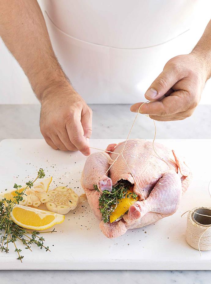 Tucking in the wings and tying the legs together allows the chicken to cook through uniformly.