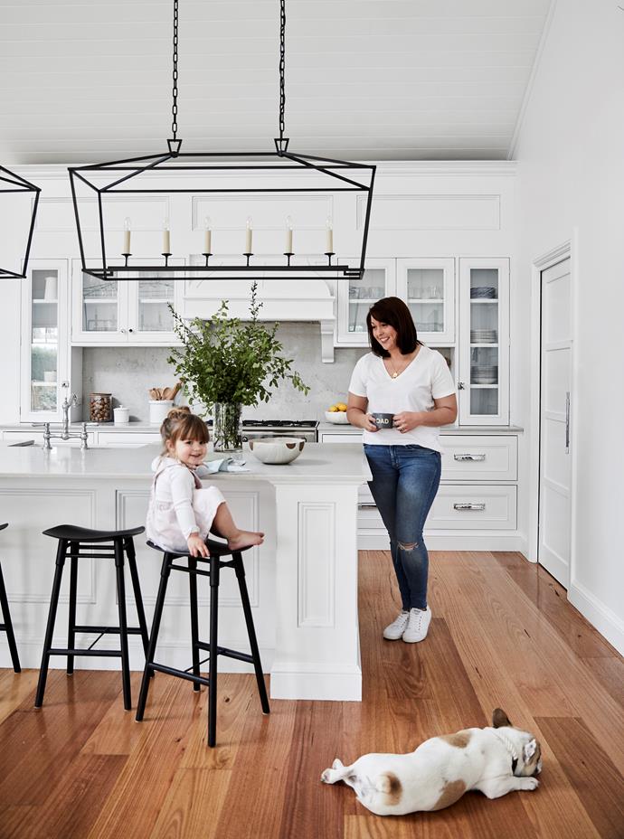 "We opted for an all-white kitchen because it always feels bright and fresh," says Brielle, pictured with Audrey and French bulldog Bert. Benchtops and splashback are Caesarstone Noble Grey. Bowl, Busatti. EF Chapman Darlana Linear pendant lights, The Montauk Lighting Co. Dowel stools, Mr Fräg.
