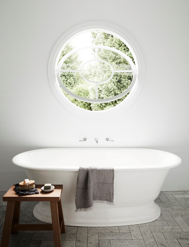Curves abound in [this bright bathroom](https://www.homestolove.com.au/family-home-with-character-in-the-nsw-southern-highlands-20547|target="_blank"), with the Victoria+Albert Elwick bath hugging the wall beneath a tilting circular window. Wall-mounted fittings allow for maximum tub loungeability.