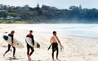 Three surfers on a beach in Mollymook, NSW