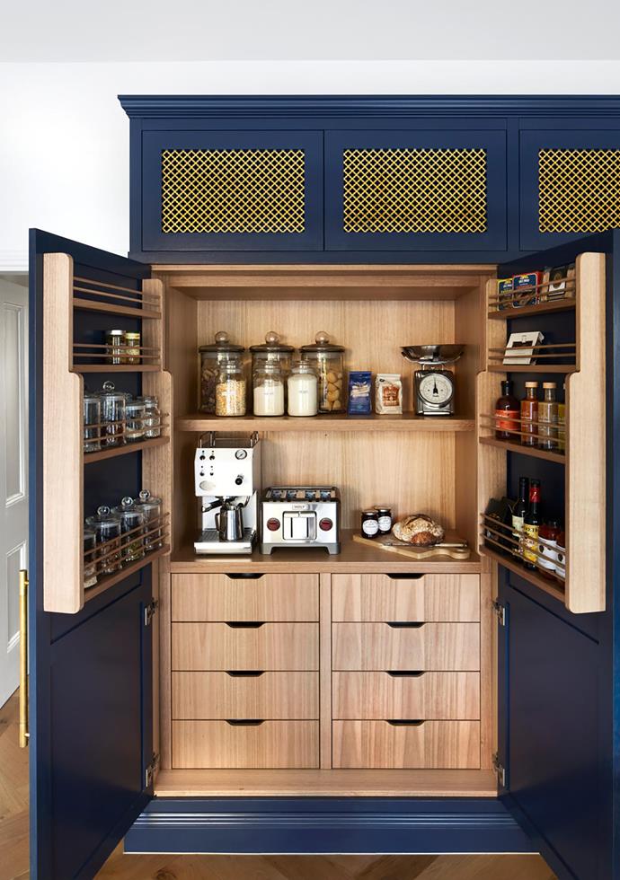 A hidden bench and spice rack in a kitchen created by interior designer Kate Walker. The cabinetry was custom made for the space and features solid oak shelving and drawers.