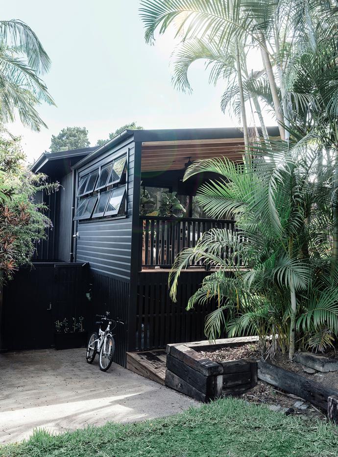 **Dare to go dark:** Painting the [home's exterior a dark colour](https://www.homestolove.com.au/dark-home-exteriors-20285|target="_blank") accentuates its linear details and helps the house blend in with its tropical surrounds.