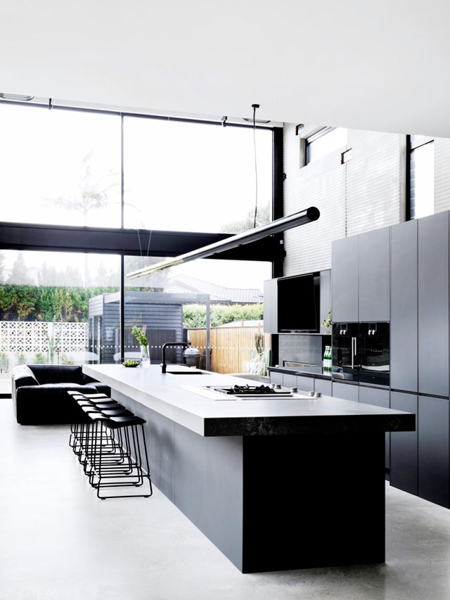 Soaring ceilings and sky-high windows let light flood into [Guy Sebastian's modern black kitchen](https://www.homestolove.com.au/guy-sebastian-kitchen-20668|target="_blank"), preventing it from feeling overly dark. A large island bench, abundant storage, a butler's pantry to hide mess, and an urban-industrial vibe make this space an entertainer's delight.
