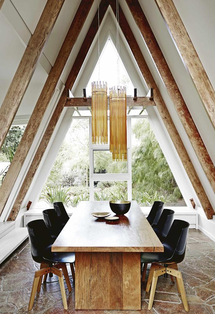 Set in this [renovated heritage home's](https://www.homestolove.com.au/a-renovated-heritage-home-with-a-point-of-difference-15501|target="_blank") unique A-frame, this dining space features the original stone floor. 
The owner made a model of the lights – Vistosi 'Diadema' pendant lamps imported from Italy – from paper and chopsticks to ensure they were hung at exactly the right height. A Mark Tuckey table is teamed with MDF Italia 'Flow' chairs from Hub Furniture.