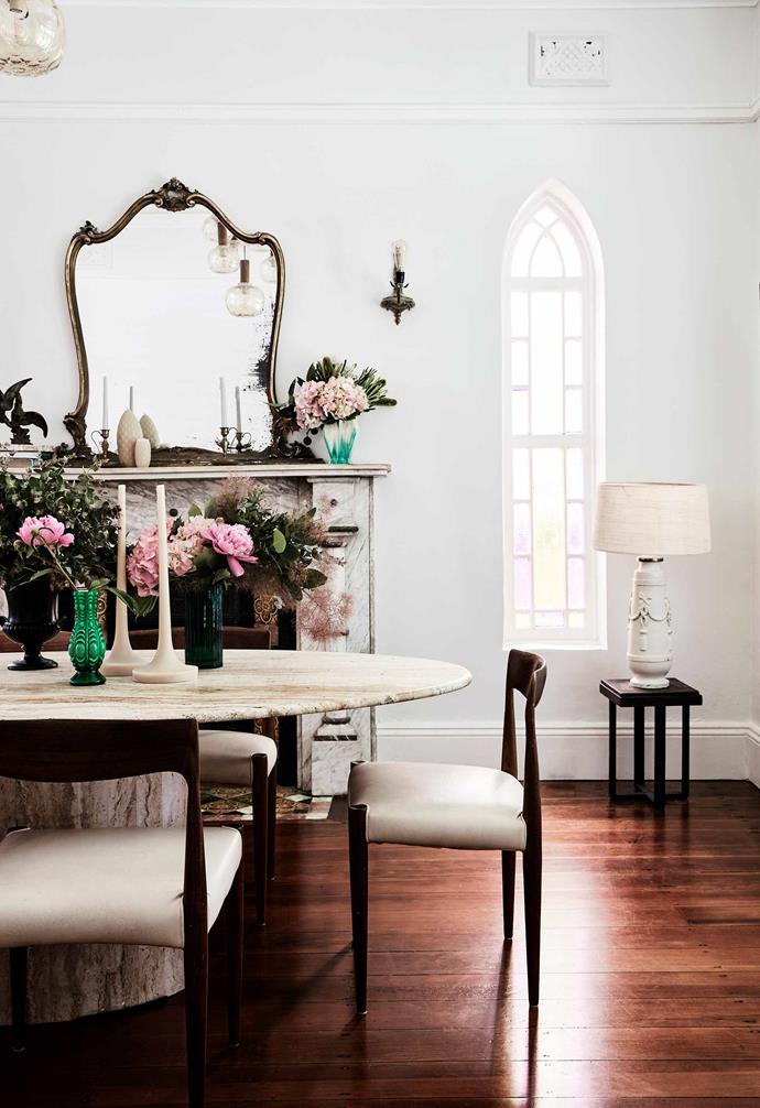 An oval travertine table is the hero of the dining room in this [Italianate Victorian home](https://www.homestolove.com.au/italianate-victorian-home-19959|target="_blank"), creating a dramatic contrast to the dark timber flooring. A well-placed mirror on the fireplace mantle maximises the natural light within the room.