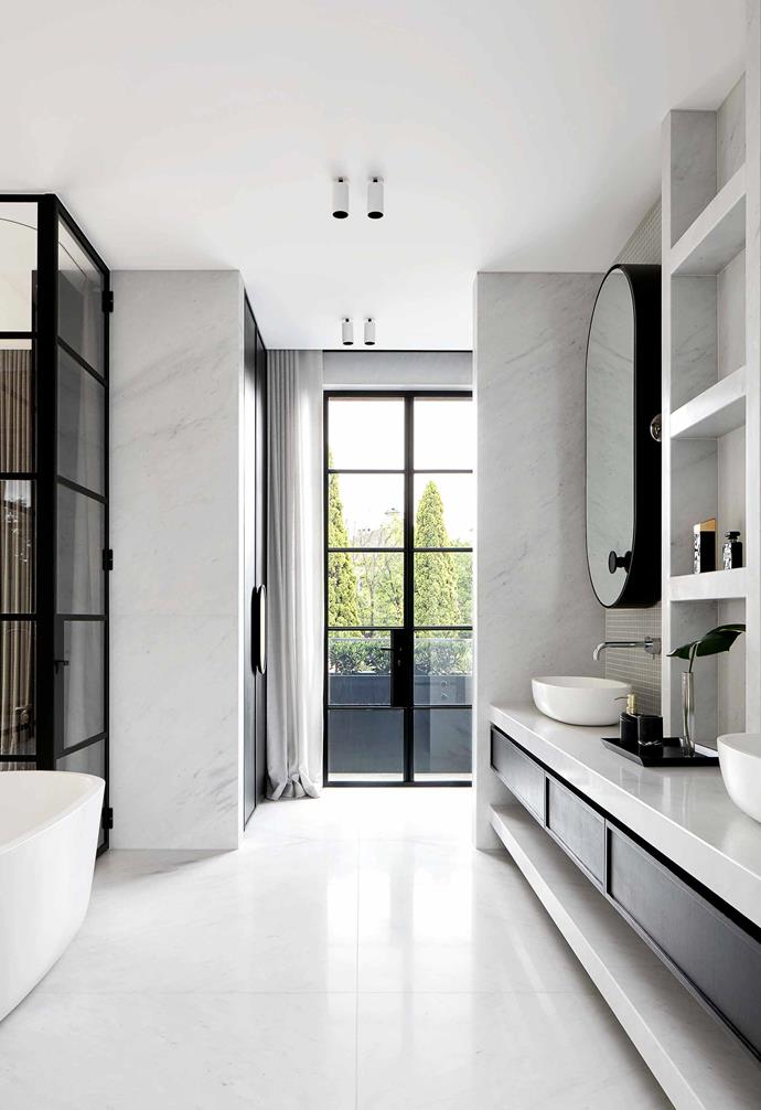 Honed Bianco Carrara marble creates a luxurious look in the bathroom of this [Victorian home in Melbourne](https://www.homestolove.com.au/two-storey-victorian-home-with-edgy-interior-melbourne-19201|target="_blank"). For contrast, statement black timber drawers are nestled underneath a white benchtop.