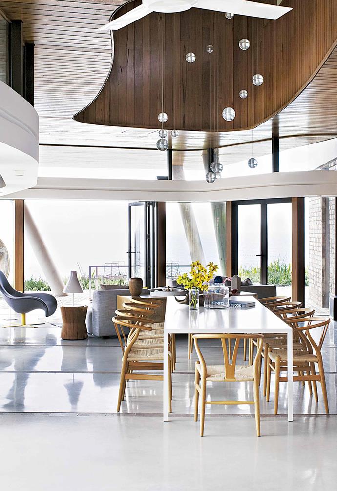 **The furniture is classic and contemporary – no driftwood of netted glass bottles?**<br><br>Lee: The owners didn't want it to be a [coastal-themed house](https://www.homestolove.com.au/8-ways-to-get-coastal-style-12277|target="_blank"). They wanted to use a lot of high-gloss white and to be colourful and fun. I also wanted to honour what Alex had achieved through the organic materials. I pushed Australian designs, so quite a lot of pieces are from [Jardan](https://www.jardan.com.au/|target="_blank"), and there are some beautiful recycled pieces. The side tables in the living space are made from telegraph poles recovered from the Queensland floods.<Br><br>**Dining area** A table with 'Wishbone' chairs and a custom Bocci '21 Series' chandelier from Hub gives a sense of scale.