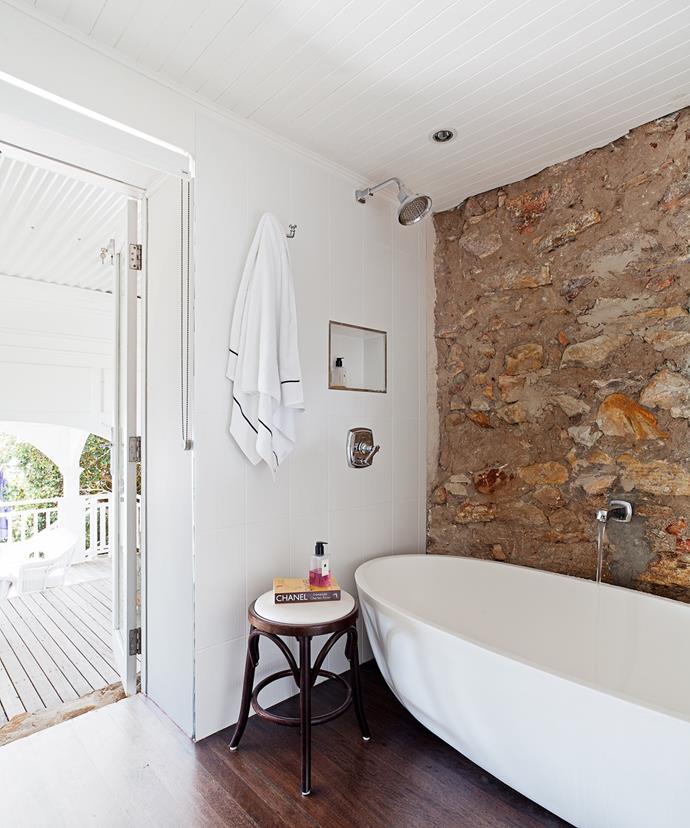 The bathroom in this [Hamptons style home](https://www.homestolove.com.au/how-to-get-the-hamptons-look-3523|target="_blank") expertly pairs a modern bath tub against an exposed sandstone wall.
