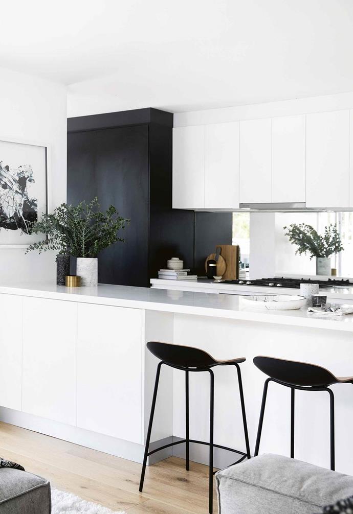 [This monochrome, open plan kitchen](https://www.homestolove.com.au/minimalist-apartment-northern-beaches-17911|target="_blank") is visually extended with the mirrored splashback to double the effect of textural accents and invite the outside in. 