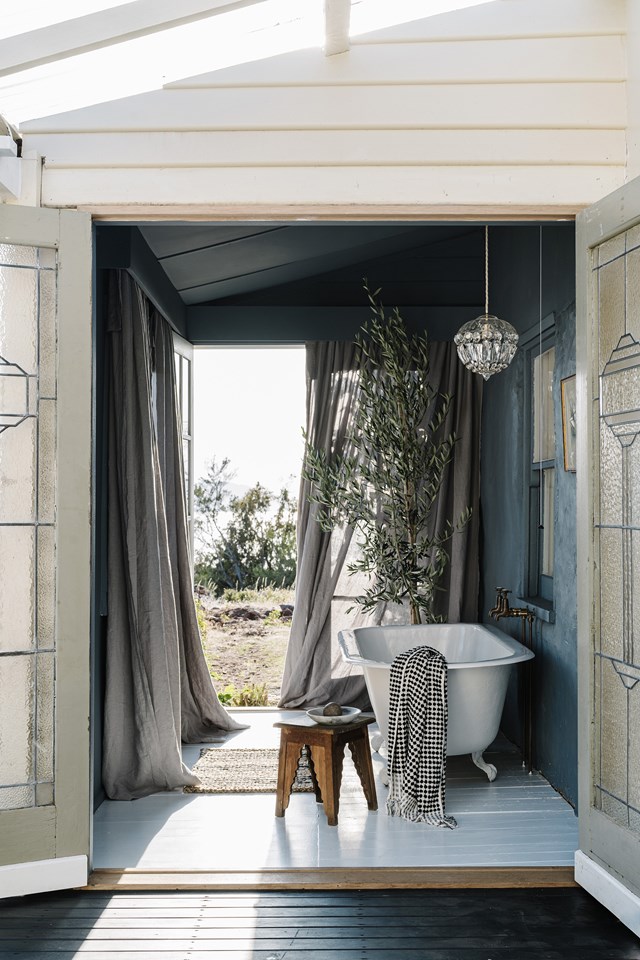 If there was ever a bathroom designed to celebrate its natural surrounds, this is it. This outdoor bathhouse at [The Burrows in Swansea, Tasmania](https://www.homestolove.com.au/the-burrows-swansea-tasmania-21597|target="_blank"), can only be accessed from the garden or deck and, with doors that open at either end, it gives you the feeling of bathing outdoors. Salvaged elements like the claw-foot bath, found in a friend's shed and restored by the couple, the chandelier and the Art Deco doors give the space a rustic charm.