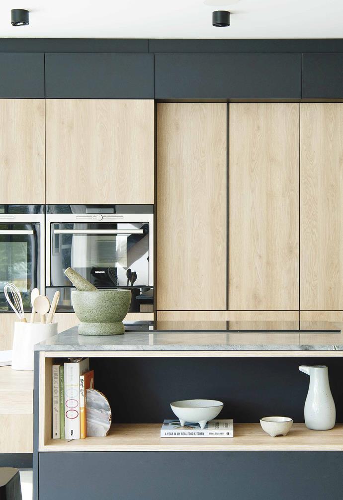 A granite benchtop from CDK Stone is paired with matt black and blonde timber laminate to create a cosy kitchen space in this [modular barn-style home](https://www.homestolove.com.au/barn-style-house-19831|target="_blank").