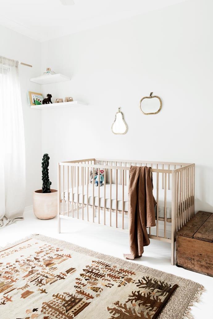 The decor in Lara Fell's baby nursery is kept simple and considered to create a serene, clutter-free space and a [neutral baby room](https://www.homestolove.com.au/how-to-set-up-a-nursery-room-20369|target="_blank") which suits their [Byron Bay home filled with hand-crafted finds](https://www.homestolove.com.au/a-byron-bay-home-filled-with-handcrafted-finds-19045|target="_blank"). The neutral colour palette flows into the nursery, which is decorated with a vintage rug and fruit-shaped mirrors from Tigmi Trading.