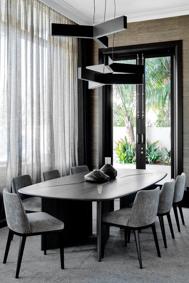 The moody dining room in this [exceptional family home](https://www.homestolove.com.au/opulent-family-home-21827|target="_blank") conceived by Christian Lyon features a 'Boomerang' dining table by Christian that sits below a cluster  of black Christopher Boots 'Bucky' pendant lights with silver leaf interior from Editeur.