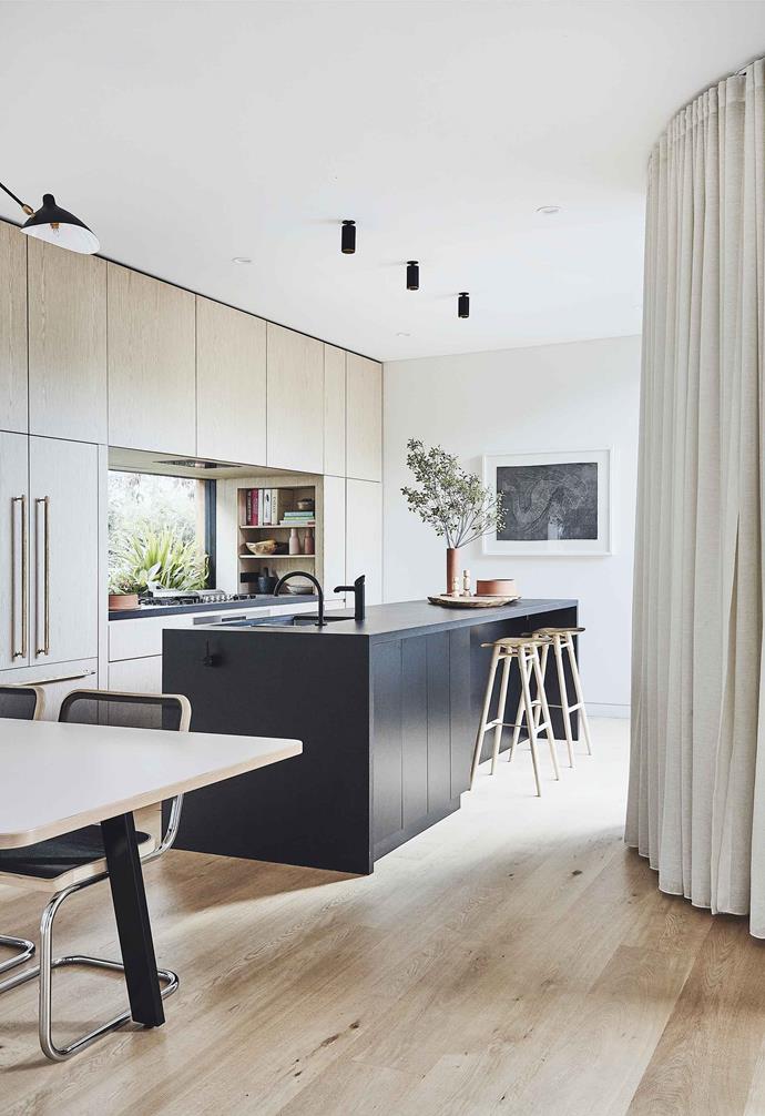 **Coastal retreat** The dark [kitchen island](https://www.homestolove.com.au/kitchen-inspiration-13-of-the-best-island-benches-17943|target="_blank") at the heart of this [Scandi-noir home](https://www.homestolove.com.au/scandi-noir-house-20344|target="_blank") helps to ground the coastal blonde timber tones throughout the space.