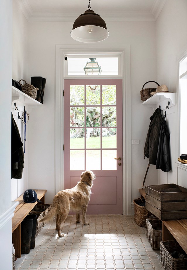A pink door is the focus of this [French-inspired home's](https://www.homestolove.com.au/modern-farmhouse-french-interior-21917|target="_blank") mud room entrance which is equal parts stylish and functional. Storage baskets, open shelving and wall hooks provide plenty of storage for muddy boots, rain coats, and hats.
