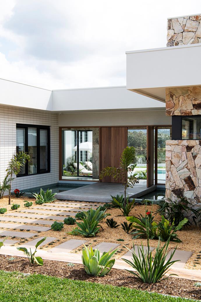 Stepping stones set into gravel, low-lying succulents and leafy shrubs surround the modernist facade of this [resort-style home](https://www.homestolove.com.au/resort-style-new-build-blue-mountains-21984|target="_blank") in the Blue Mountains. Two pool-style ponds sit either side of the door, creating a fusion between Palm Springs and Balinese style gardens that works a treat.