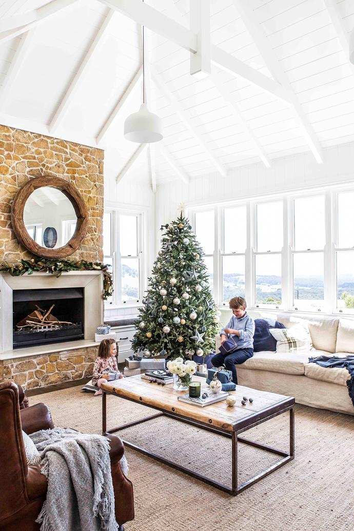In the sun-drenched [lounge room](https://www.homestolove.com.au/lounge-room-ideas-21182|target="_blank"), a garland from West Elm adorns the mantel, while cushions and throws from Eadie Lifestyle evoke a holiday mood. The fireplace tells a story of provenance as the stone was salvaged from the site during excavation. "It gave us an opportunity to recycle," explains Louise (top left with John, Charlotte and Harry). The floors are Massivo oak boards with a custom stain from Tongue N Groove and the walls are painted in Dulux Antique White USA Quarter. "I wanted it almost white, with just a soft tint," says Louise. The presents are wrapped elegantly and simply with fabric that was sourced from Spotlight.
