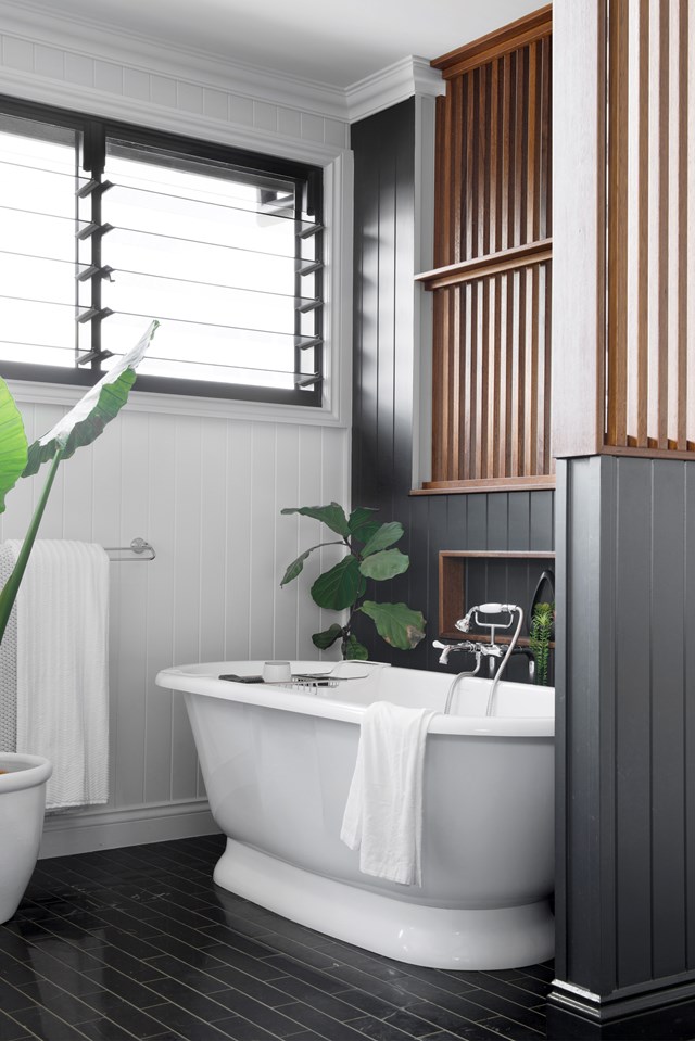 Modern meets traditional in the design of [this newly built Brisbane home](https://www.homestolove.com.au/modern-new-build-brisbane-22028|target="_blank"), where a Victoria + Albert 'Elkwick' bath sits beneath louvered windows and slatted timber privacy screens. Painted in Dulux Black Caviar, VJ panelled walls marry new with old and separate the ensuite from the main bedroom.