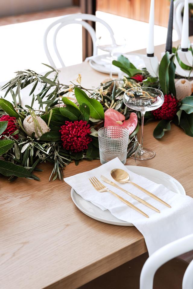 Interweaving banksia, waratah, protea, olive leaf, aranthera and anthurium along the centre of this [festive table](https://www.homestolove.com.au/sloping-corner-block-house-design-19523|target="_blank") makes a sweet-scented alternative to a textile runner.