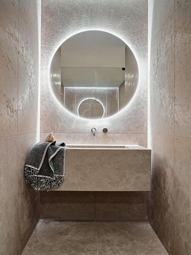 The backlit mirror in the powder room of [this Great Ocean Road](https://www.homestolove.com.au/great-ocean-road-home-with-naturalistic-interior-22075|target="_blank") property illuminates the rough, organic texture of the Cristallo quartzite.