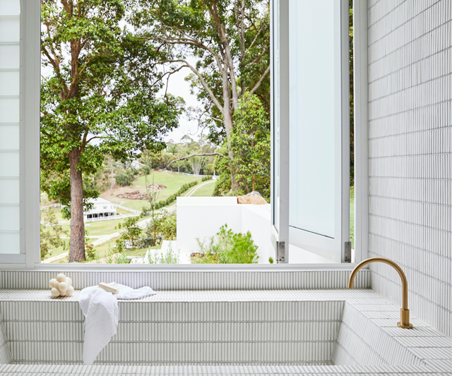 An inset bath becomes a feature in this Byron Bay bathroom that's dressed head-to-toe in finger tiles.