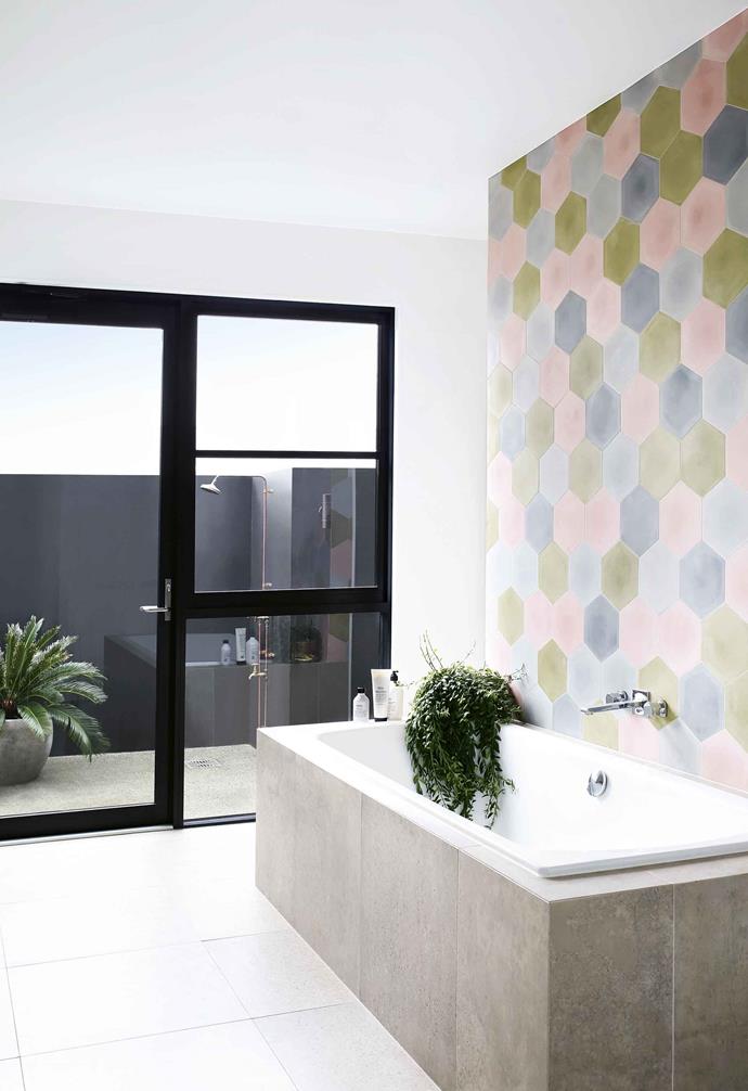 In this [Palm Springs-inspired home](https://www.homestolove.com.au/palm-springs-mid-century-casuarina-18340|target="_blank") the owners incorporated a pastel palette throughout several key spaces. In the bathroom, this palette is highlighted with a playful mix of pale pink, grey and green hexagonal tiles that create a striking feature wall above an inset bathtub clad in grey tiles.<br><br>