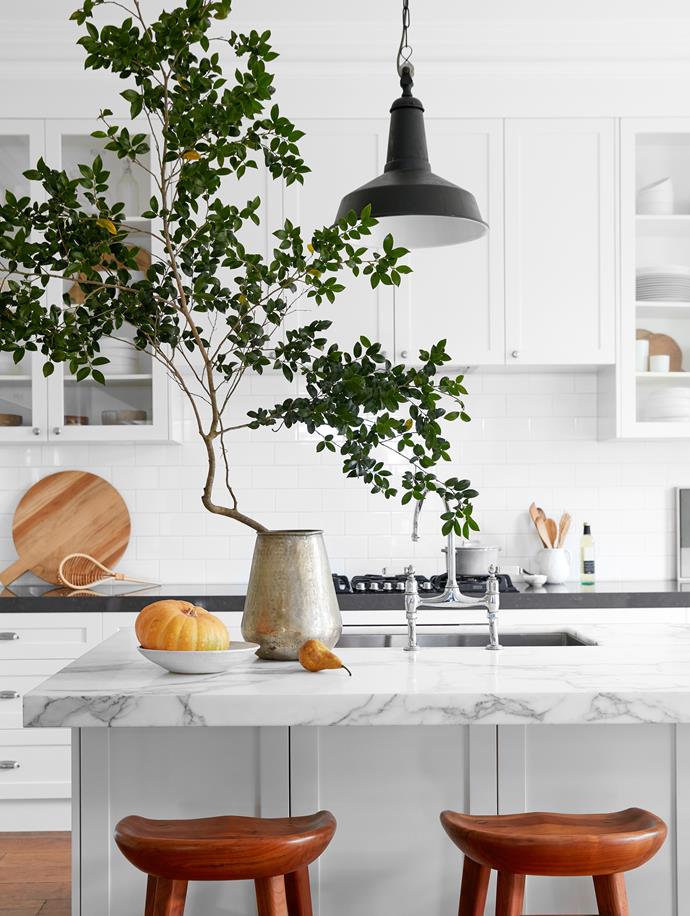 Wondering how to add personality to an all-white kitchen? Take style cues from this [sandstone home in Mosman](https://www.homestolove.com.au/redecorated-sandstone-house-mosman-22442|target="_blank"). A leafy branch imparts freshness to the space, while layered wooden utensils add warmth. 